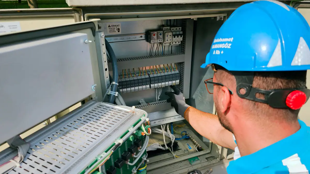 An electrician in a hard hat working on a switchboard